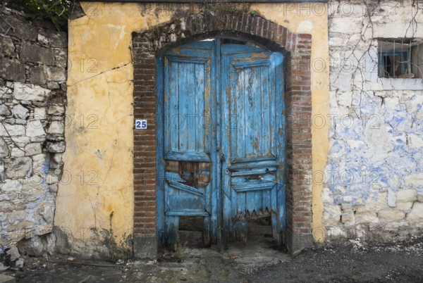 Entrance of an abandoned house with a blue damaged wooden door from a traditional house in Cyprus
