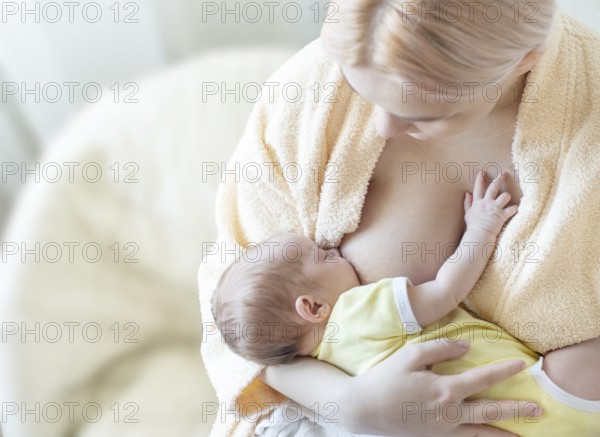 Baby eating breast milk. Caucasian blonde young mother breastfeeding her baby horizontal photo. Concept of lactation
