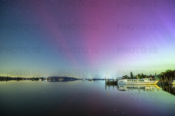 Calmness of the lake at night with starry sky, northern lights and a boat in the background, harbour, Allensbach, Lake Constance, Baden-Württemberg, Germany