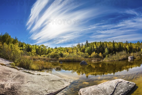 Indian summer in Manitoba, Canada. Incredible cirrus clouds over the Winnipeg River. Old Pinawa Dam Park. The concept of ecological and recreational tourism