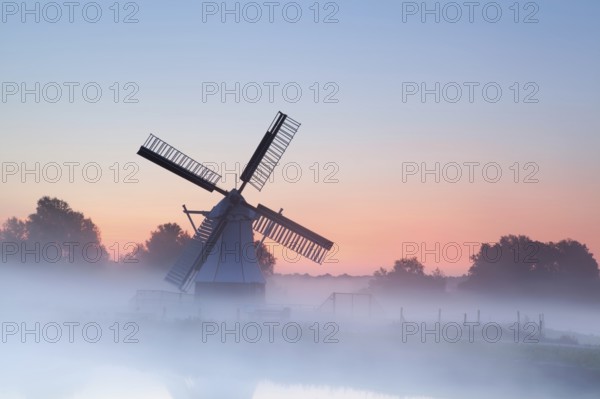 Charming Dutch windmill in morning sunrise fog, Groningen, Netherlands