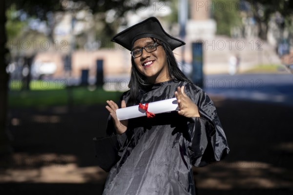 Latin transgender woman recent graduated, dressed in cap and gown, showing off his degree celebrating