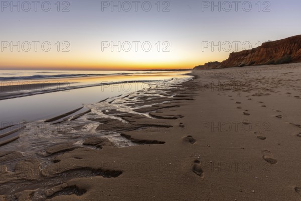 What a sandy beach on the Atlantic. Landscape shot at sunset on a coast with sandstone cliffs. Low tide on the yellow beach of Praia da Falésia near Albufeira, Algarve, Portugal