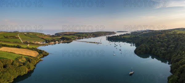 An aerial panorama landscape in warm evening light over Castlehaven Bay with many sailboats anchored