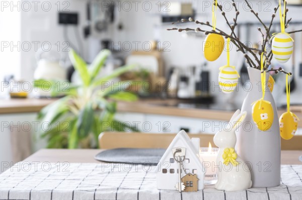 Key to house of cozy home with Easter decor with rabbit and eggs on table of kitchen. Building, design, project, moving to new house, mortgage, insurance, rent and purchase real estate