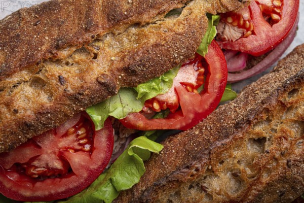 Close-up macro of dark ciabatta sandwich with green salad, ripe red tomatoes and tuna. Vegetable vegetarian sandwiches, healthy snack or lunch food, food photography, food photography