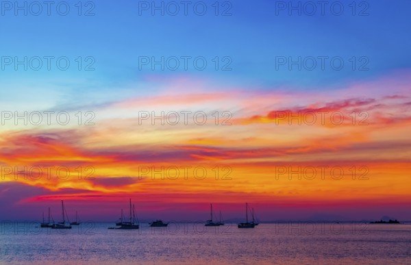 Yachts boats in front of the most beautiful colorful sunset at Tropical Paradise island Koh Phayam Ao Khao Kwai Beach in Ranong Thailand