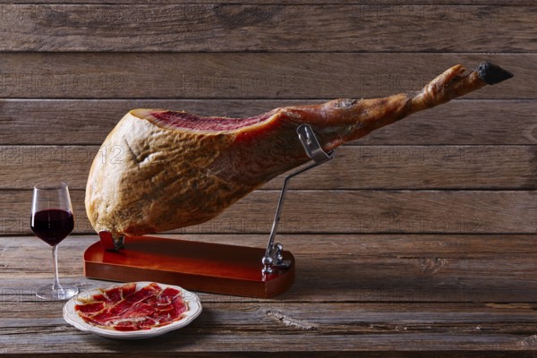 Iberian ham pata negra from Spain with red wine on wood background