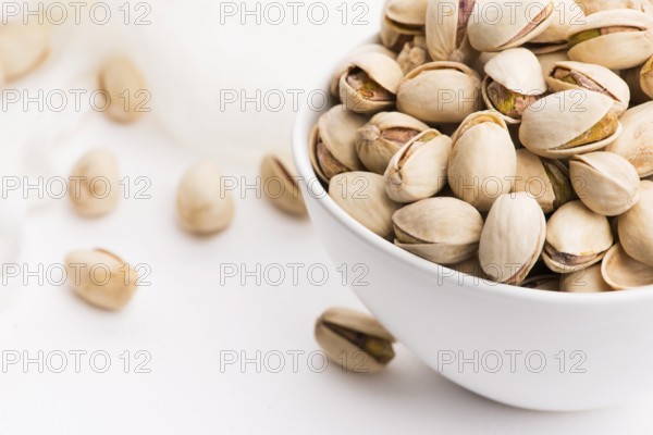 Bowl of roasted pistachios on a white background