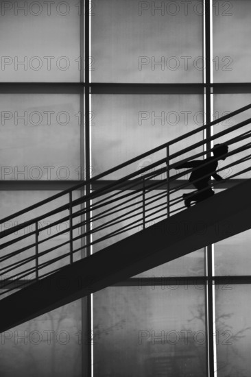 The silhouette of a boy climbing a staircase in a stooped posture