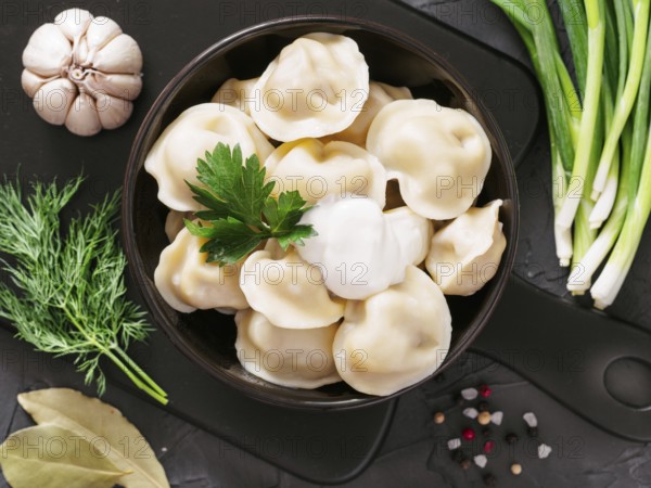 Traditional russian pelmeni, ravioli, dumplings with meat on black concrete background. Top view or flat lay. Russian food and russian kitchen concept