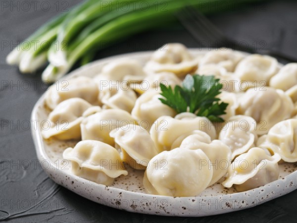 Traditional russian pelmeni, ravioli, dumplings with meat on black concrete background. Russian food and russian kitchen concept