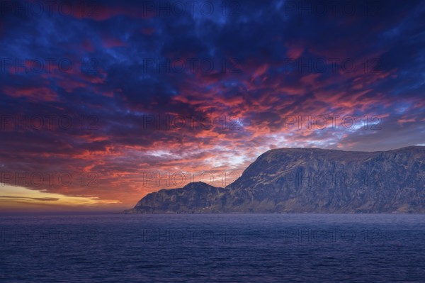 View from the sea to the West Cape in Norway at sunset with sun rays and heavy clouds. Waves in the foreground, rocks in the background. Westernmost point of Europe mainland