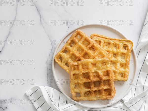 Perfect savory keto waffles. Two ingredients chaffles on plate over white marble background. Eggs and parmesan cheese low carb waffles. Top view or flat lay. Copy space for text or design