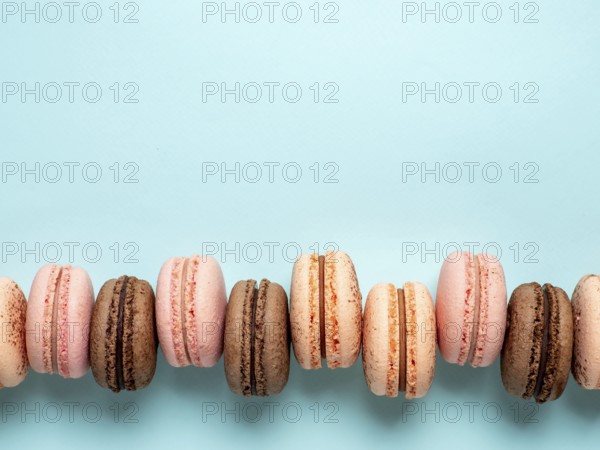 Macarons with copy space. Row of perfect french macarons or macaroons on blue background. Top view or flat lay