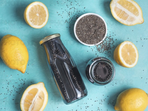 Detox activated charcoal black chia water or lemonade with lemon on bright blue background. Two bottle with black chia infused water. Detox drink idea and recipe. Vegan food and drink. Top view