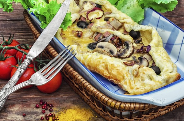 Baking with dough with meat and mushrooms in glass form and kitchen fork and knife