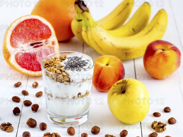 Healthy breakfast: yogurt with muesli and chia seeds, fruits and nuts on white wooden background. Dieting, healthy lifestyle concept meal