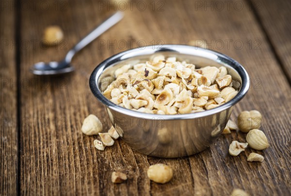Portion of freshly chopped Hazelnuts on an old wooden table as detailed close up shot (selective focus)