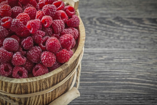 Raspberries in bucket on vintage wooden board horizontal image