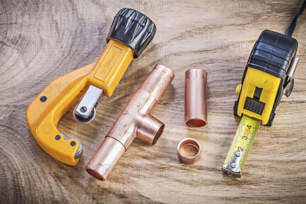 Copper water pipe cutter connectors tape measure on wood board plumbing brassware concept