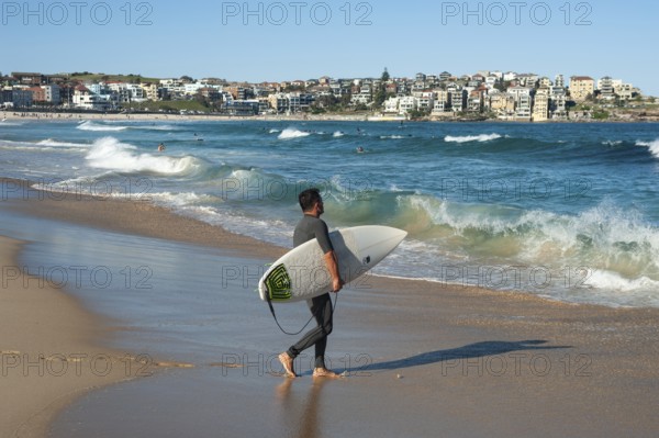 21.09.2018, Sydney, New South Wales, Australia, A surfer walks with his surfboard under his arm towards the sea at Bondi Beach