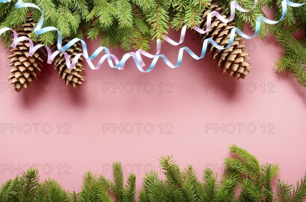 Flat lay design of Christmas greeting card of fir twigs cones and paper streamer on pink background. Space for text