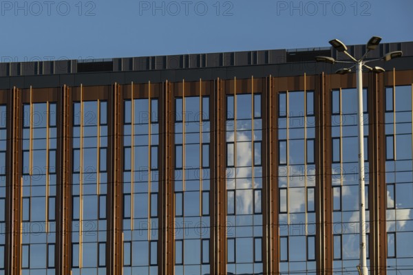 Modern office building exterior with glass facade on clear sky background. Transparent glass wall of office building with yellow decoration. Element of facade of modern European building Commercial office buildings. Abstract modern business architecture