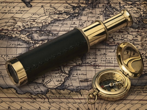 Travelling theme: vintage telescope and compass at antique map