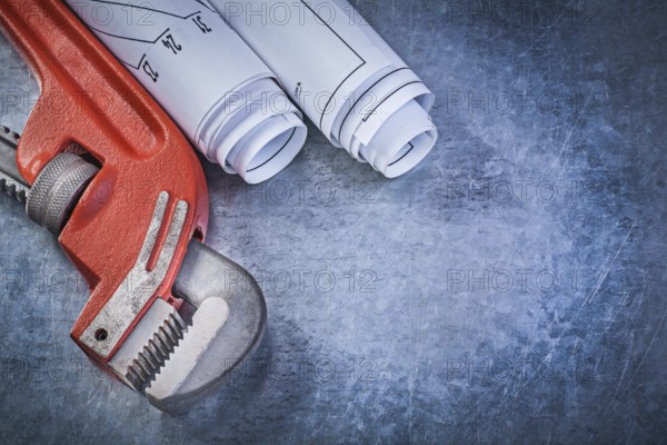 Monkey wrench rolled engineering drawings on metallic background plumbing concept