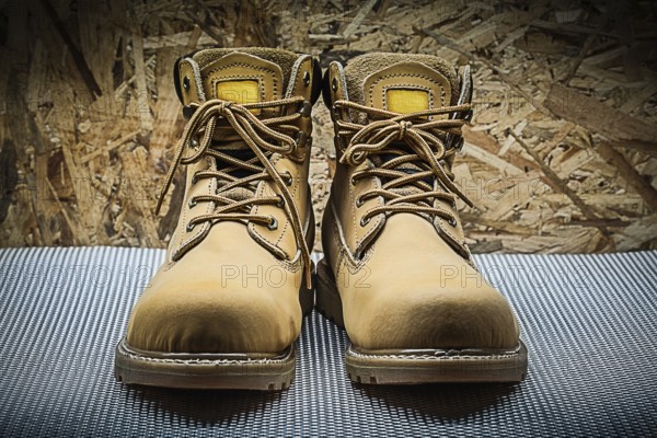 Two brown working boots on plywood background
