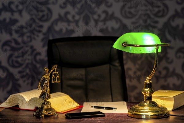 Office of a lawyer with books and a statue of Lady Justice, goddess Justitia, on the desk
