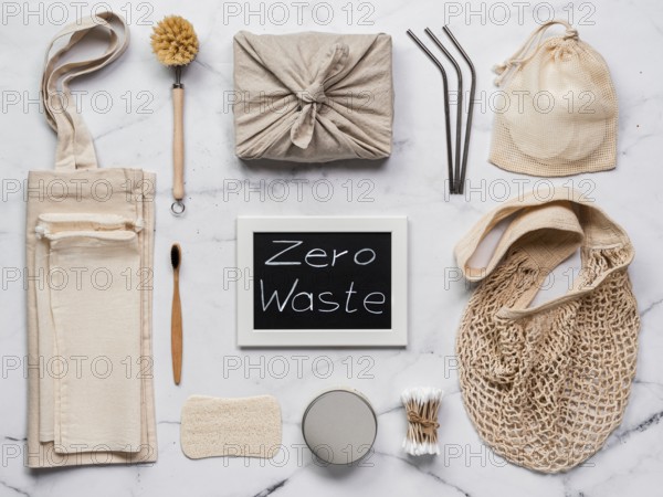 Zero waste concept. Textile wrapping gift, eco bags, metal straws, eco-friendly kitchen tools, bamboo toothbrush and cotton buds, reusable cotton pads on white marble background. Top view or flat lay
