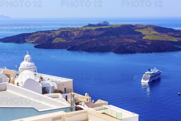 Santorini, Greece iconic view of white houses, church dome, caldera, volcano island and sea panorama with cruise ship