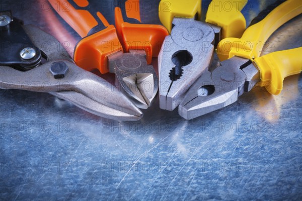Close up view of tin snips gripping tongs nippers on scratched vintage metallic surface construction concept