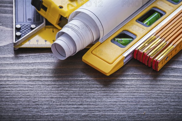 Wooden meter try square measuring tape blueprints and construction level on vintage wood board maintenance concept