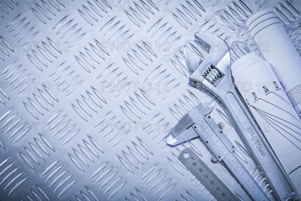 Engineering drawings vernier caliper monkey spanner on channeled metal background construction concept