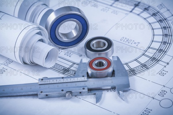 Rolls of construction plans rolling bearings and slide caliper on blueprint industrial concept