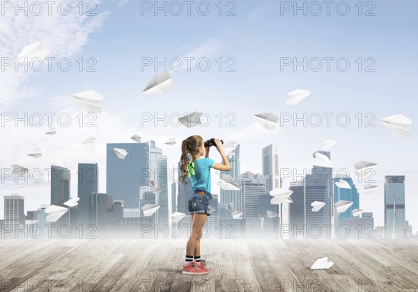 Concept of careless happy childhood with girl looking in binoculars