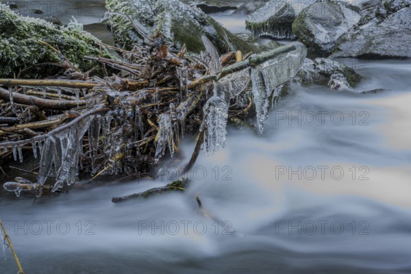 Frozen branches over a fast flowing river depicting a cold, frosty winter landscape, Perlbachtal, Lower Bavaria