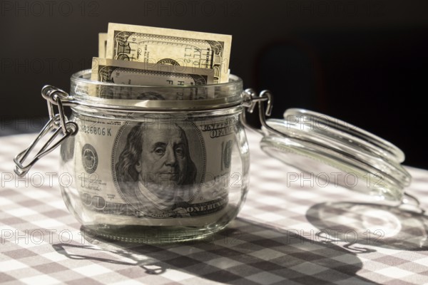 Dollar banknote saving money in glass jar. Consumption and economy Collecting money. Tips. Business, finance, saving, banking and people concept. Extra money, passive income. Saving for travel, crisis, house, car, education, retirement