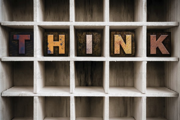 The word THINK written in vintage ink stained wooden letterpress type in a partitioned printer's drawer