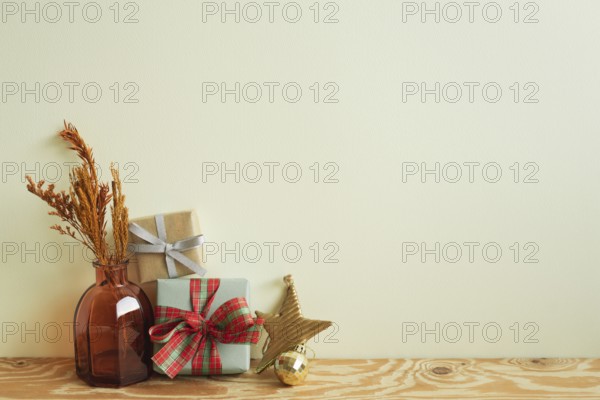 Gift boxes, vase of dry flower, christmas ornament on wooden table. ivory wall background. winter christmas, copy space