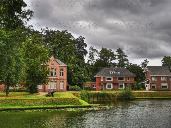 Houses on the lakeshore, surrounded by trees and plants, with a cloudy sky, groenlo, gelderland, the netherlands