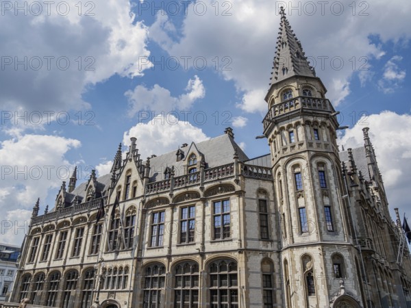 Large historic building with Gothic architecture and towers under a blue sky with clouds, Ghent, Belgium