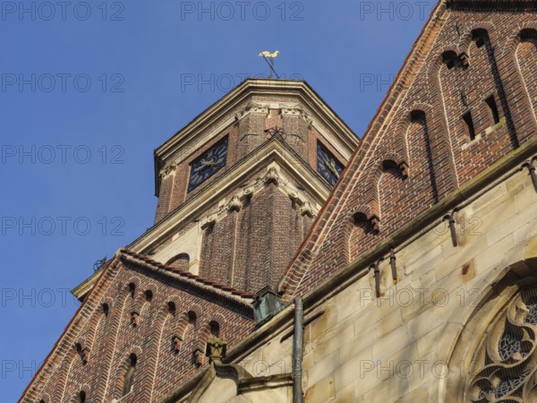 A pointed brick church tower with decorative details and clock under a bright blue sky, Coesfeld, Münsterland, North Rhine-Westphalia, Germany