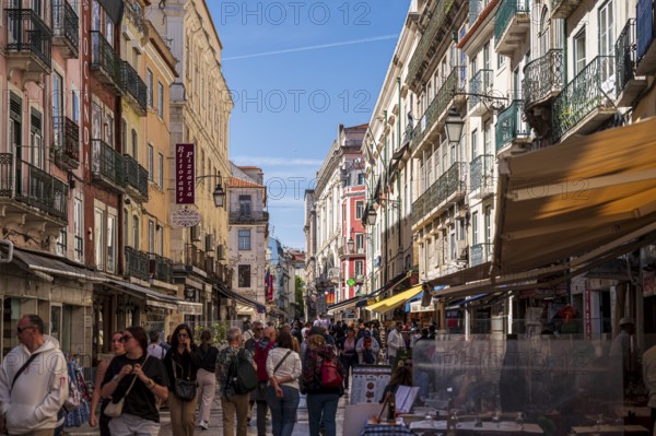Busy shopping street in Lisbon, Lively city street with many people, surrounded by colourful buildings under a clear blue sky, Lisbon, Portugal
