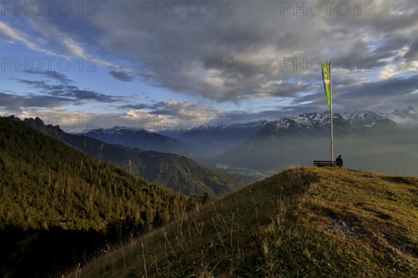 Sitting woman enjoying a dreamlike evening mood in the mountains, view to the Rätikon, flag of the Austrian Alpine Club, Frassenhütte, Vorarlberg, Austria