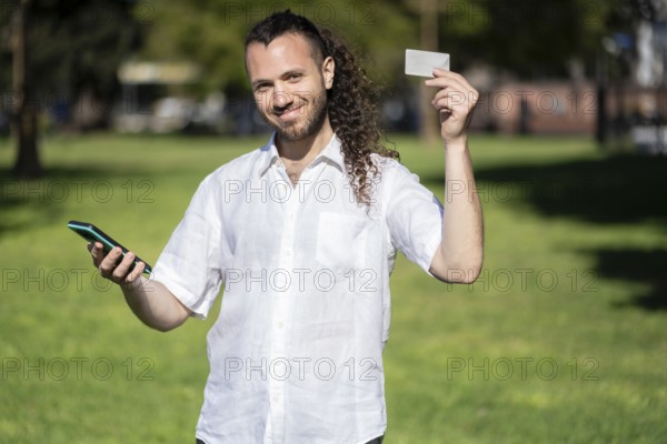 Young man making an online purchase with his credit card and his phone