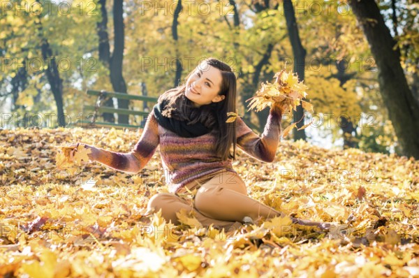 Beautiful girl in autumn Park keeps yellow leaves